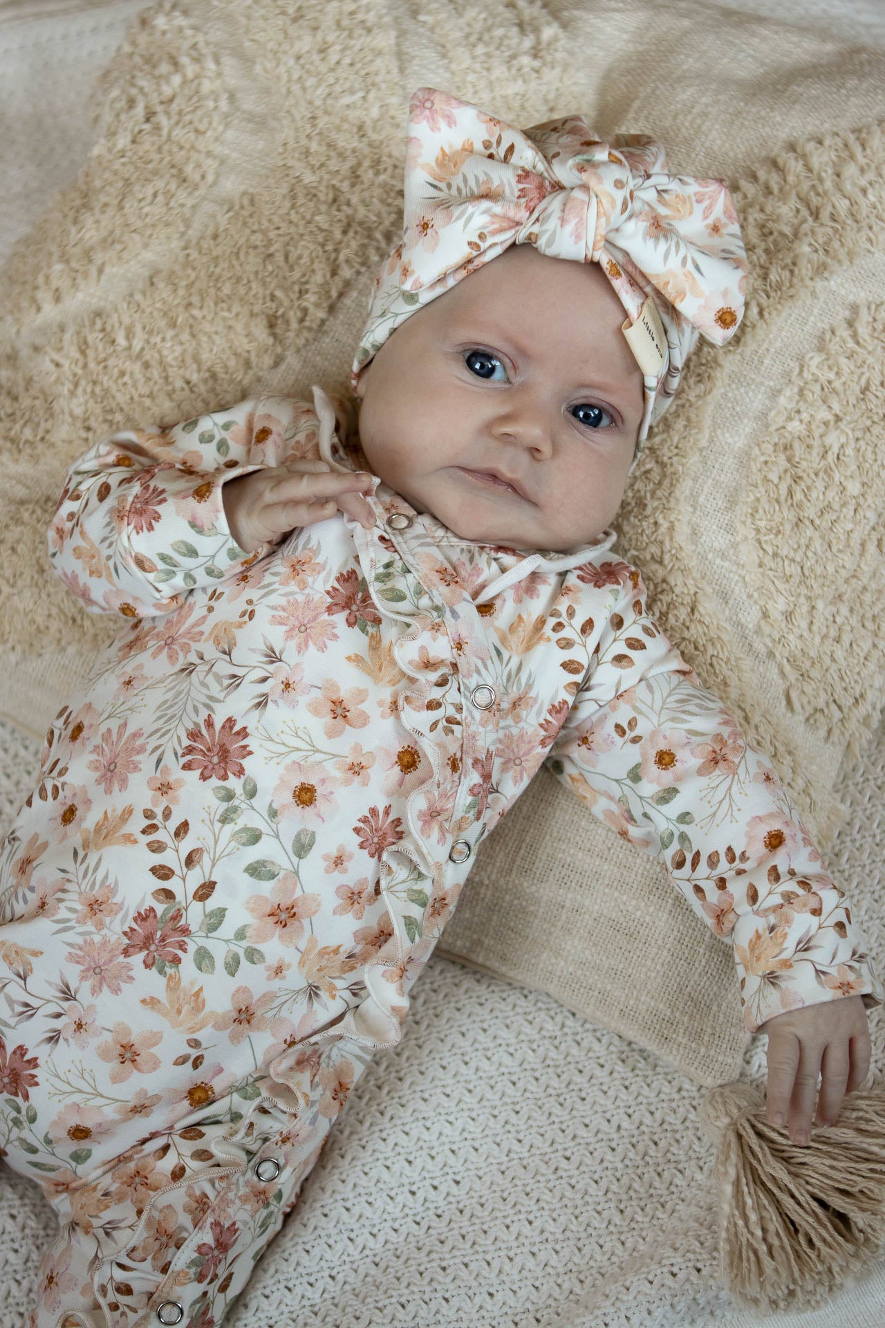 Pfirsichfarbener Strampler mit Rüschen und Blumen